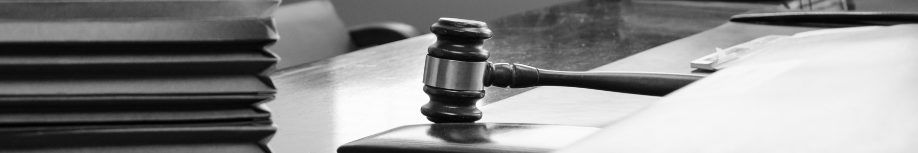 Black and white photo of desk with gavel and paper files.