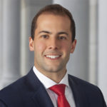 Anthony M. DeLongis smiling wearing a red tie and a navy blazer.